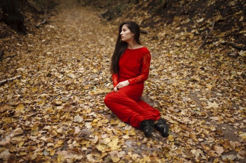Caucasian woman sitting in autumn leaves