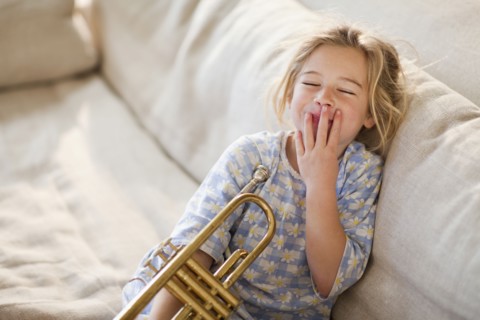 Caucasian girl sitting on sofa with trumpet