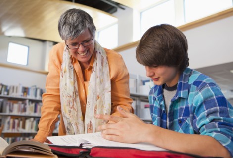 Librarian helping boy with homework in library