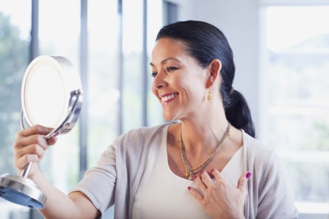 Hispanic woman trying on jewelry in store