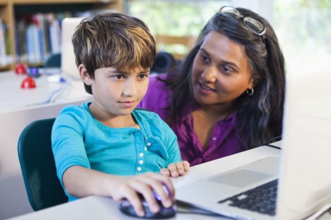 Teacher helping student using laptop