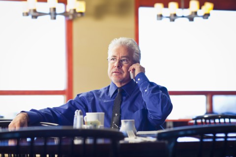Hispanic cafe owner talking on cell phone