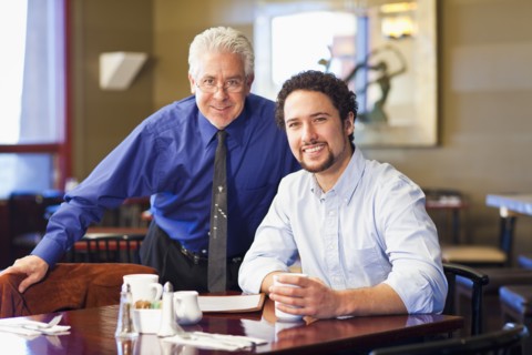 Businessmen smiling together in cafe