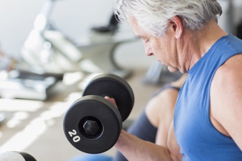 Older Hispanic man lifting weights in gym