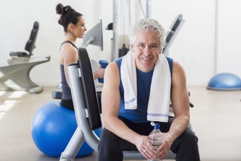 Older Hispanic man smiling in gym