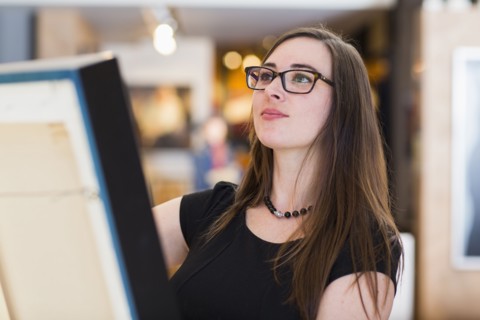Caucasian woman examining painting in art gallery