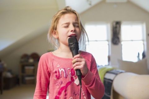 Caucasian girl singing karaoke at home