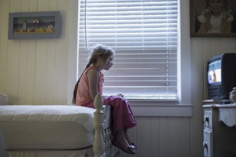 Caucasian girl watching television on bed