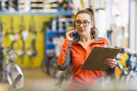 Caucasian woman talking on telephone in bicycle shop