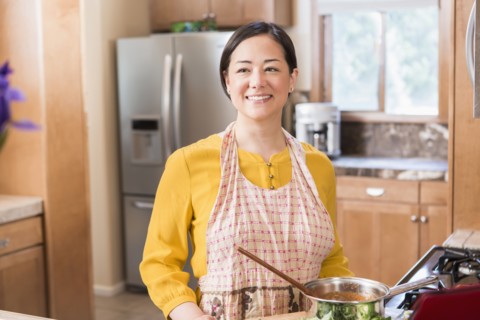 Mixed race woman cooking in kitchen