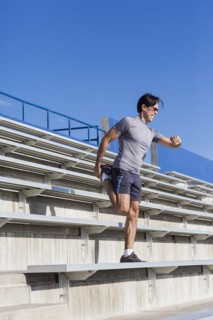 Hispanic athlete stretching on bleachers