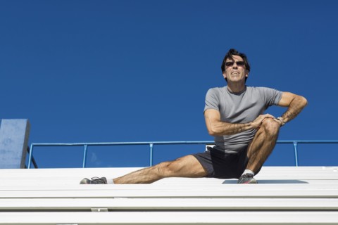 Hispanic athlete stretching on bleachers