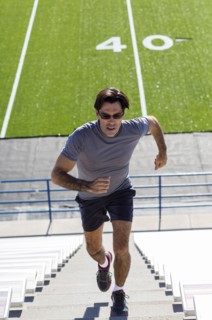 Hispanic athlete running on bleacher steps