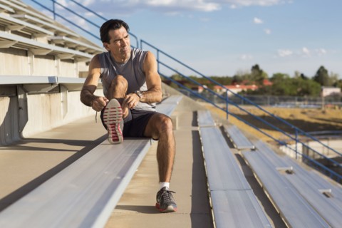 Hispanic athlete resting on bleachers