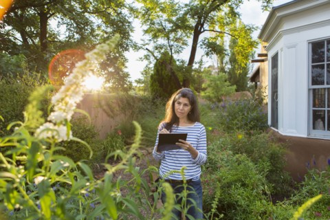 Hispanic woman sketching flowers in garden
