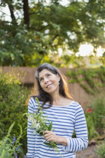 Hispanic woman holding flowers in garden