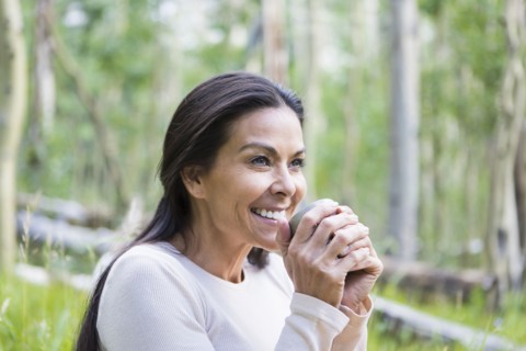 Hispanic woman having cup of coffee outdoors