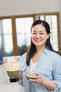 Mixed race woman drinking green smoothie