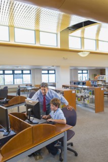 Teacher and student working at computer in library
