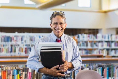 Senior man holding books in library