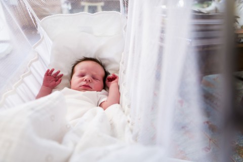 Caucasian newborn baby boy laying in crib