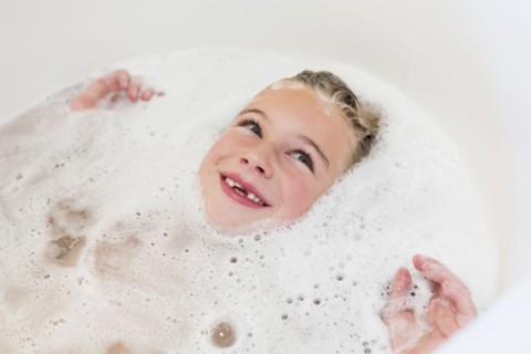 Caucasian girl laying in bubble bath