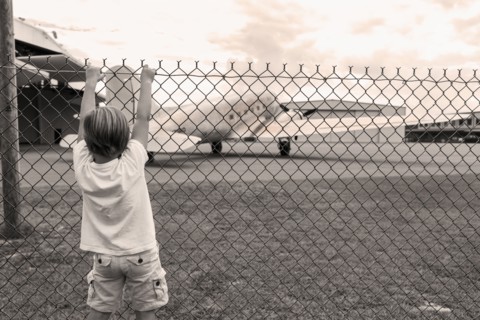 Boy climbing chain link fence around airport