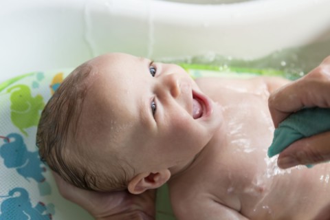 Caucasian mother giving baby boy a bath