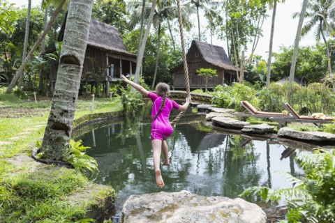 Caucasian girl swinging on rope in garden