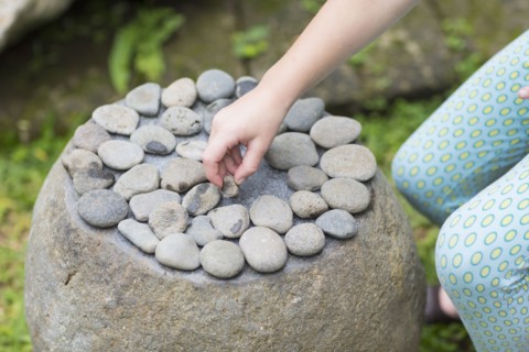 Caucasian girl arranging stones on boulder
