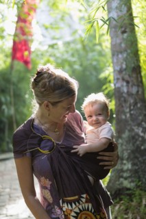 Caucasian mother carrying baby in rainforest