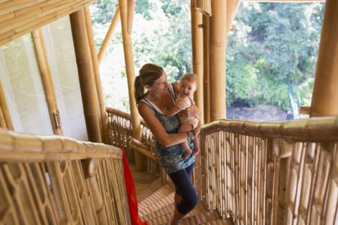 Caucasian mother carrying baby up stairs