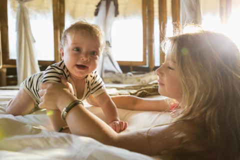 Caucasian children playing on bed
