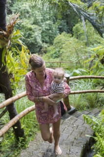 Caucasian mother carrying baby up steps in jungle landscape