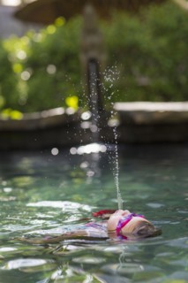 Caucasian girl spraying water in swimming pool