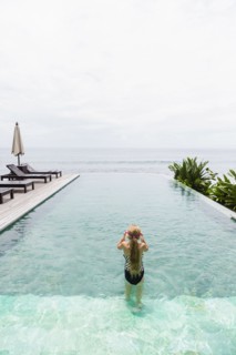 Caucasian girl swimming in infinity pool