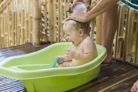 Caucasian baby having bath in tub