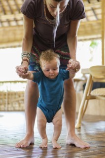 Caucasian mother helping baby walk