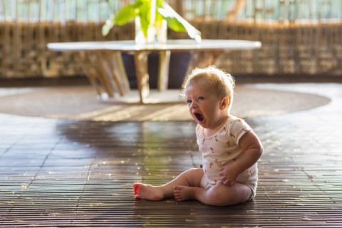 Caucasian baby yawning on floor
