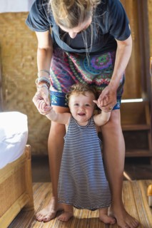 Caucasian mother helping baby stand