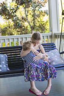 Caucasian girl holding brother on porch swing