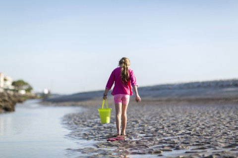 Caucasian girl carrying bucket on beach
