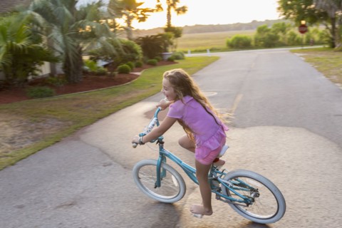 Caucasian girl riding bicycle on street