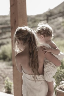 Caucasian girl carrying baby brother on porch