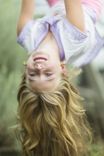 Caucasian girl hanging upside down outdoors