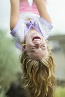 Caucasian girl hanging upside down outdoors