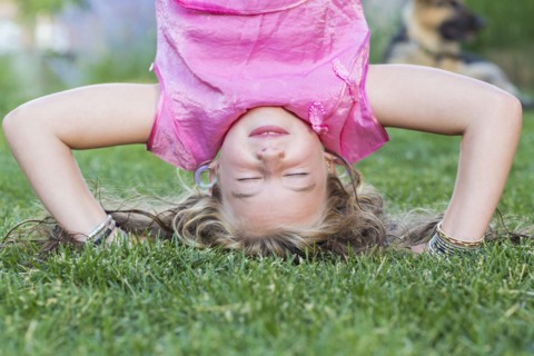 Caucasian girl doing headstand in grass