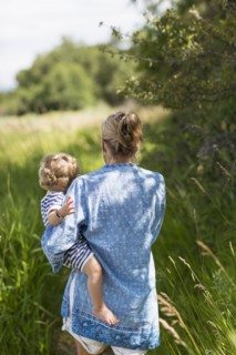 Caucasian mother carrying baby son in grassy field