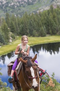 Caucasian girl riding horse in near lake