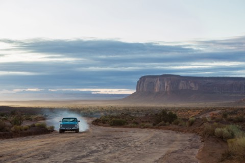 Car driving on dirt road in desert